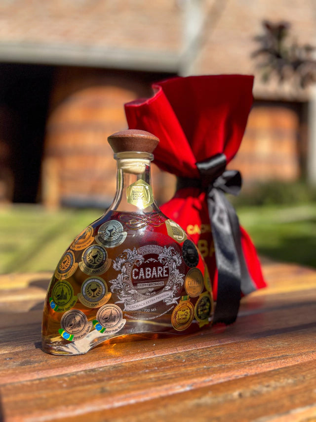 Botella de Cachaça Cabaré Extra Premium 15 años sobre fondo de madera con lazo rojo